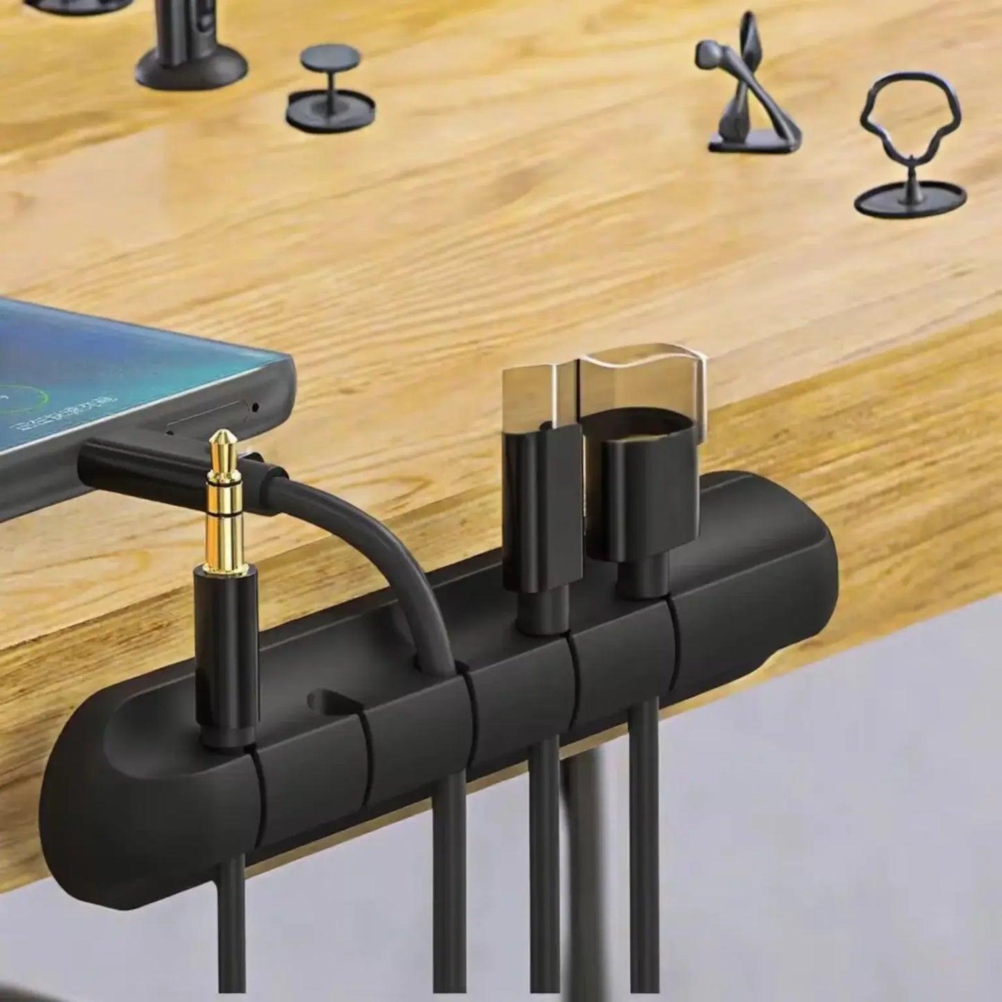 Black cable organizer with phone and earbuds on a wooden surface