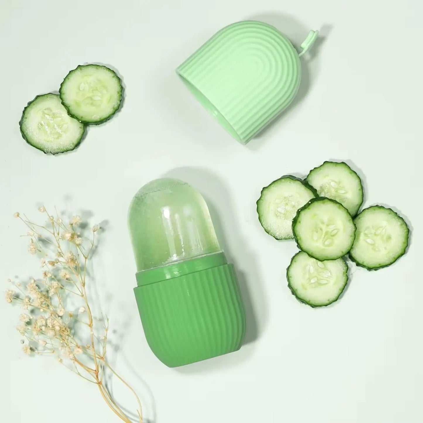 Green container with lid, sliced cucumbers, and dried flowers on a light background