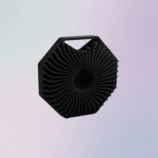 Black, textured, hexagonal scrubber on a gradient background