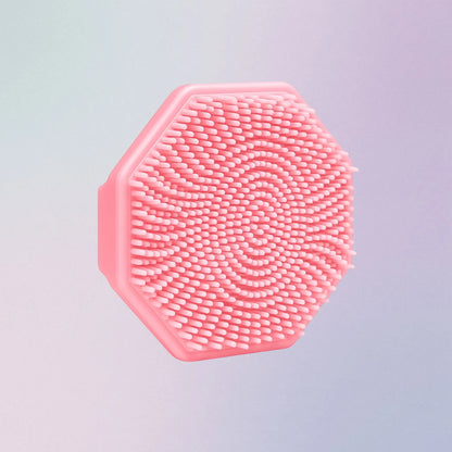 Pink silicone face scrubber with soft bristles and finger grip